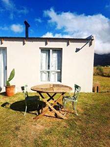 a picnic table and two chairs in front of a house at Cornelia's Field in Joubertina