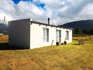 Cornelia's Field في Joubertina: بيت أبيض صغير مع طاولة في حقل