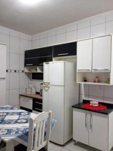 een keuken met een witte koelkast en een tafel bij Casa Pé na Areia in Mongaguá