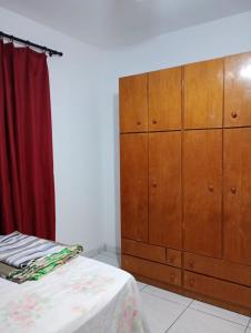 een slaapkamer met een grote houten dressoir naast een bed bij Casa Pé na Areia in Mongaguá