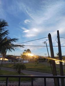 een uitzicht op de zonsondergang vanaf een straat met een hek bij Casa Pé na Areia in Mongaguá +12 foto's