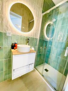 Un baño con lavabo y ducha con espejo. en The happy garage at the beach, en La Cala de Mijas