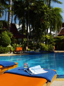 a table with a glass of wine next to a swimming pool at Safari Beach Hotel Patong in Patong Beach