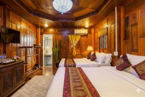 Suchanan Resort Rayong في بان تشانغ: سريرين في غرفة مع جدران وسقوف خشبية +54 صورة