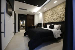 a bedroom with a large bed and a stone wall at Il Moro Luxury Rooms in Siracusa