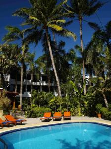 a swimming pool with orange chairs and palm trees at Safari Beach Hotel - SHA Extra Plus in Patong Beach