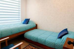 Smart Rentals - Agradable departamento en Mantagua في Estación Mauco: غرفة نوم بسريرين ونافذة ذات وسائد زرقاء +15 صورة