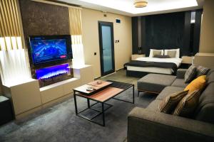 a living room with a couch and a bed and a tv at LİMONOTTO SUİT OTEL in Mersin