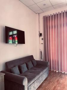 Cloudy homestay في Bảo Lâm: غرفة معيشة مع أريكة وتلفزيون على الحائط