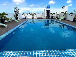a large blue swimming pool with chairs and a building at Cozy private jacuzzi spa apartment in Casablanca