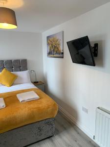 Un dormitorio con una cama con un televisor de pantalla plana en la pared. en City & Station Apartments at Gulland House by Pureserviced, en Plymouth
