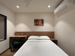 a bedroom with a bed and a desk and a table at Round D Clock, IGI Airport in New Delhi +6 photos