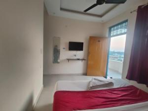 a bedroom with a bed with a red blanket and a window at JD Hotel in Doiwāla