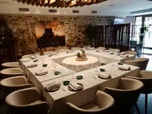einen langen Tisch mit weißen Tischen und Stühlen in einem Zimmer in der Unterkunft Restaurante & Hotel Rural El Mirador de Trevejo,ideal para parejas in Villamiel