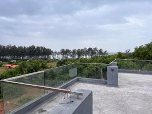 Casa Oceanus - Sea Facing Forest View Room - Ganpatipule في Nevra: شرفة على سور فوق المبنى