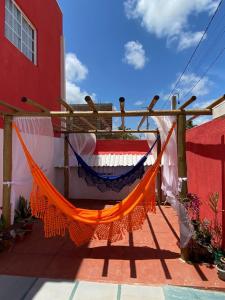 een oranje hangmat aan de zijkant van een rood gebouw bij Suítes Concha do Sol in Maragogi