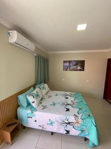 een slaapkamer met een bed met een blauw dekbed bij Suítes Concha do Sol in Maragogi +1 foto