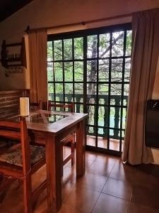 a dining room with a table and a large window at Cabañas Lorelei in Villa General Belgrano +6 photos
