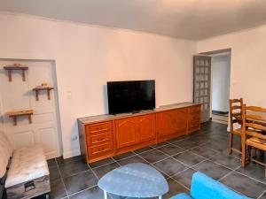 Gîte Le Coquelicot Jardins de Marie في Cerizay: غرفة معيشة مع تلفزيون بشاشة مسطحة على خزانة خشبية