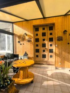 Gîte Le Coquelicot Jardins de Marie في Cerizay: غرفة بطاولة وجدار خشبي