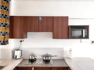 Makasembo furnished apartments one bedroom في كيزيمو: مطبخ مع قدورين على موقد مع ميكروويف