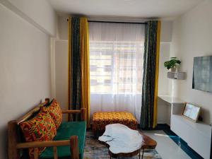 Makasembo furnished apartments one bedroom في كيزيمو: غرفة معيشة مع كرسي ونافذة
