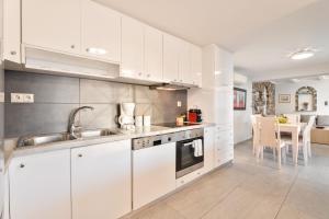 Una cocina con gabinetes blancos y un fregadero y una mesa. en Villa Suites Lagonisi Luxury, en Lagonisi