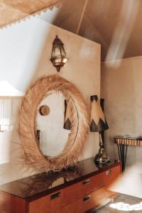 Agafay Yes We Camp Restaurant & Spa في Aït Mazou: مرآة على رأس خزانة مع مصباح