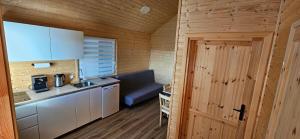 a small kitchen in a wooden cabin with a door at Perłowy Port in Gąski