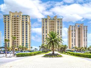 un palmier devant deux grands bâtiments dans l'établissement Beach Colony East 8D By Pkrm, à Pensacola