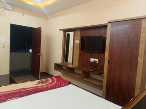 a bedroom with a bed and a tv on a wall at Jaya SriRama Lodge in Bhadrāchalam