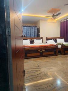 a bedroom with two beds and a ceiling fan at Jaya SriRama Lodge in Bhadrāchalam