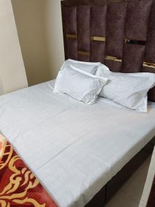 un letto con lenzuola bianche e cuscini sopra di Radhika P Guest House Ajmer welcome to all family friends groups fully airconditioner attach washroom with geeser near by railway station near by Bus stand less than 1 km a Ajmer