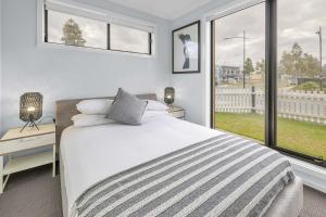 a white bedroom with a bed and two windows at Bright & Cozy 4-Bed Home in Rockbank in Rockbank +17 photos
