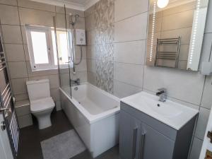 a bathroom with a sink and a tub and a toilet at Daisy Lodge in Norwich