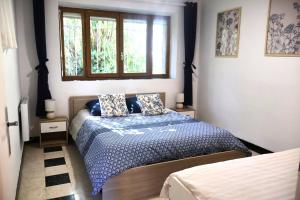 a bedroom with a bed with a blue comforter and a window at La Roseraie in Lodève