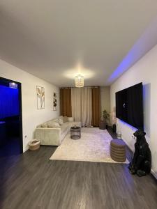Una sala de estar con un sofá y un televisor de pantalla plana. en Appartement luxueux avec jacuzzi, en Cergy