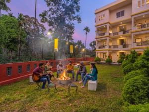 a group of people sitting around a fire in front of a building at The Hosteller Bam Coorg in Madikeri +24 photos