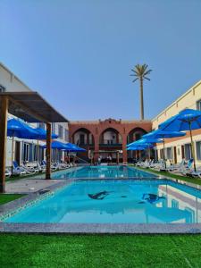 een groot zwembad met blauwe parasols bij Dahab Now in Dahab