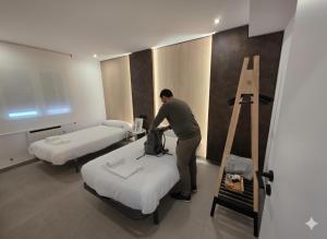 a man standing next to two beds in a room at Apartamentos Camino Inglés II in Ordes