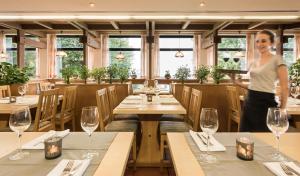 a woman standing in a restaurant with tables and glasses at Landhotel Rosenberger in Wegscheid