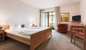 1 dormitorio con 1 cama, 1 silla y TV en Landhotel Rosenberger, en Wegscheid
