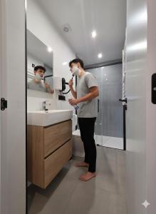 a man standing in a bathroom brushing his teeth at Apartamentos Camino Inglés II in Ordes