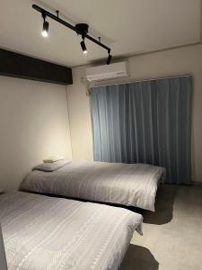 1 Schlafzimmer mit 2 Betten neben einem Fenster in der Unterkunft Miya's Home 102-名駅まるまる貸切メゾン in Nagoya