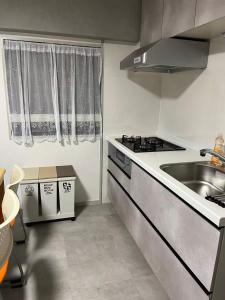 eine kleine Küche mit Spüle und Herd in der Unterkunft Miya's Home 102-名駅まるまる貸切メゾン in Nagoya