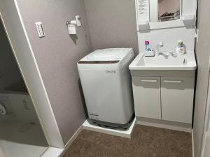 ein kleines Badezimmer mit Waschmaschine und Waschbecken in der Unterkunft Miya's Home 102-名駅まるまる貸切メゾン in Nagoya
