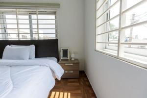 a white bedroom with a bed and a window at Maseru Apartments in Bawaleshi