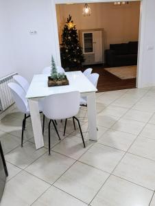 un tavolo da pranzo bianco con sedie bianche e un albero di Natale di Casa Valente a Viso 1 altra foto