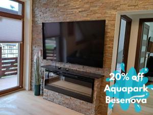 a living room with a large television on a brick wall at Apartament 325 in Bešeňová