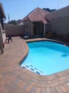 a swimming pool with a brick patio and a house at 16 Laburnum lodge in Durban